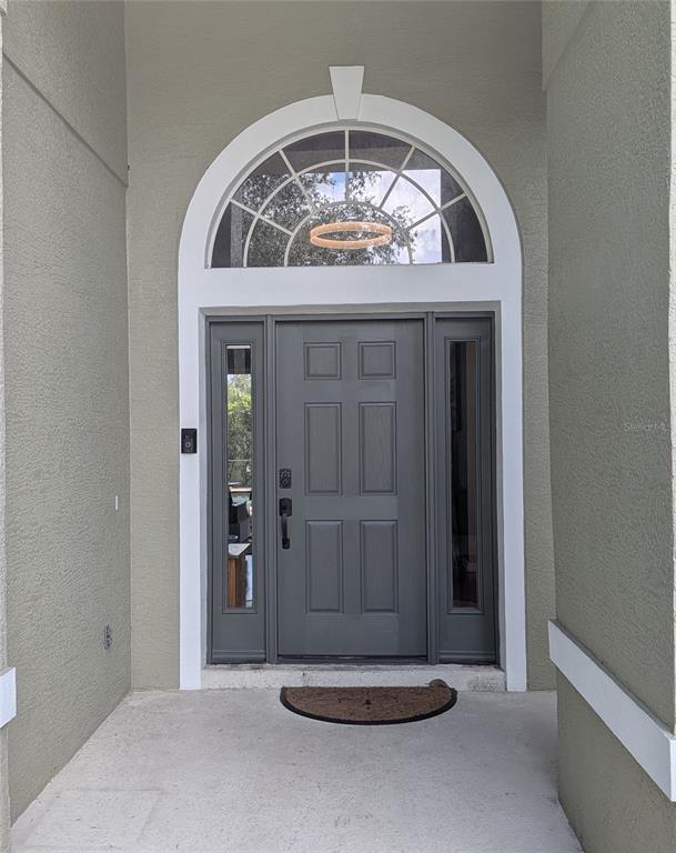 A gray front door with sidelights and an arched transom window sits in a stucco entryway — 920 SAZA RUN, CASSELBERRY, FL