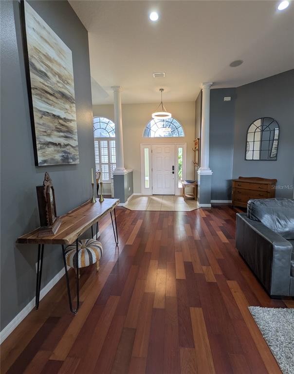 A foyer with hardwood floors, two white columns, and a live-edge wood console table — 920 SAZA RUN, CASSELBERRY, FL