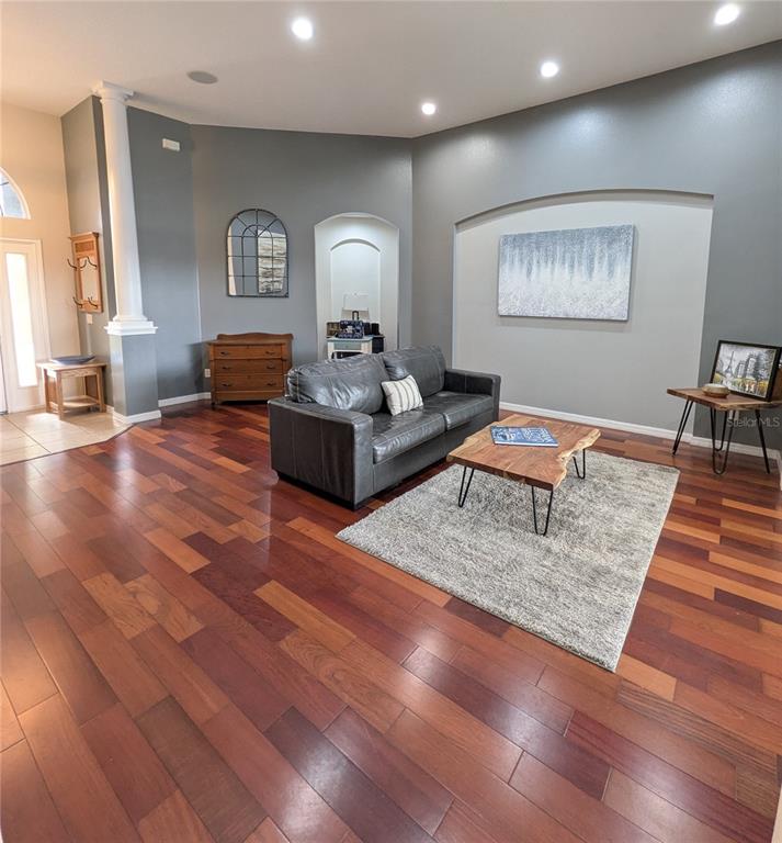 A living room features dark hardwood floors, a grey sofa, and a live-edge coffee table — 920 SAZA RUN, CASSELBERRY, FL