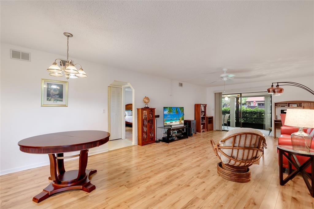 A living and dining area with wood-look flooring, a round table, and a sliding glass door — 5400 34TH STREET W UNIT B16, BRADENTON, FL