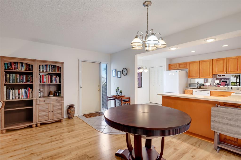 A dining area with a round table, wooden bookshelf, and an adjacent kitchen with light cabinets — 5400 34TH STREET W UNIT B16, BRADENTON, FL