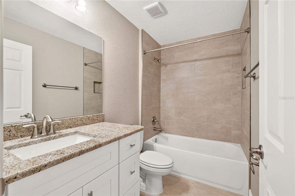 A bathroom features a white vanity with granite countertop, a toilet, and a tiled tub-shower — 19802 SW MARINE BOULEVARD, DUNNELLON, FL