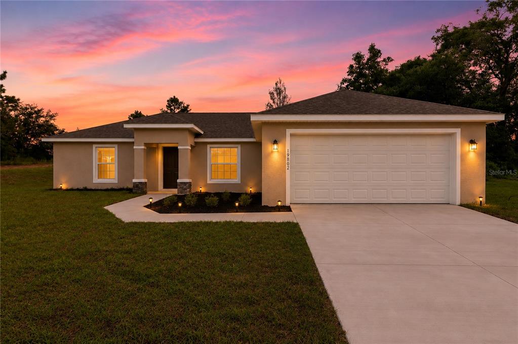 A single-story house with a two-car garage and a concrete driveway at sunset — 19802 SW MARINE BOULEVARD, DUNNELLON, FL