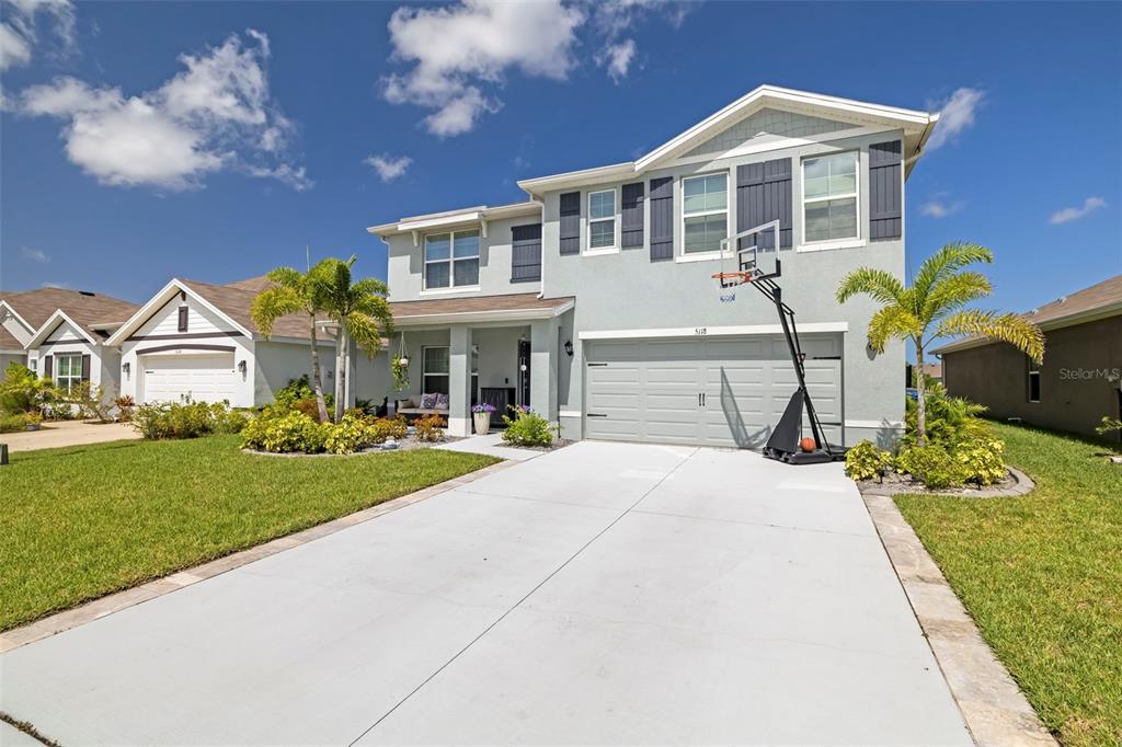 A two-story house with a light gray exterior, a concrete driveway, and a basketball hoop — 5118 ROCKY COAST PLACE, PALMETTO, FL