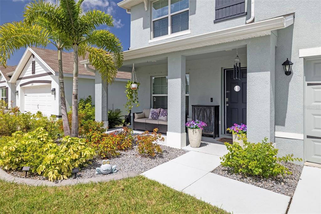 A light blue two-story house features a covered front porch, landscaping, and a palm tree — 5118 ROCKY COAST PLACE, PALMETTO, FL