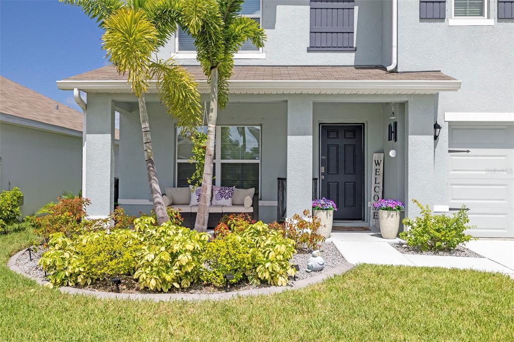 The exterior of a two-story house features a covered front porch, landscaping, and a palm tree — 5118 ROCKY COAST PLACE, PALMETTO, FL