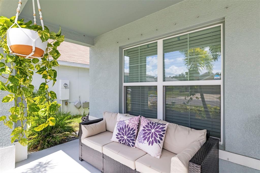 A covered patio features a wicker sofa with patterned pillows and a hanging potted plant — 5118 ROCKY COAST PLACE, PALMETTO, FL
