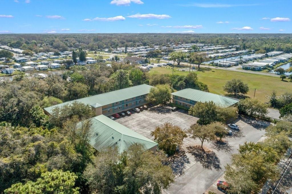 An aerial view shows a multi-story apartment complex with green roofs and a parking lot — 5816 CONGRESS STREET UNIT 203, NEW PORT RICHEY, FL