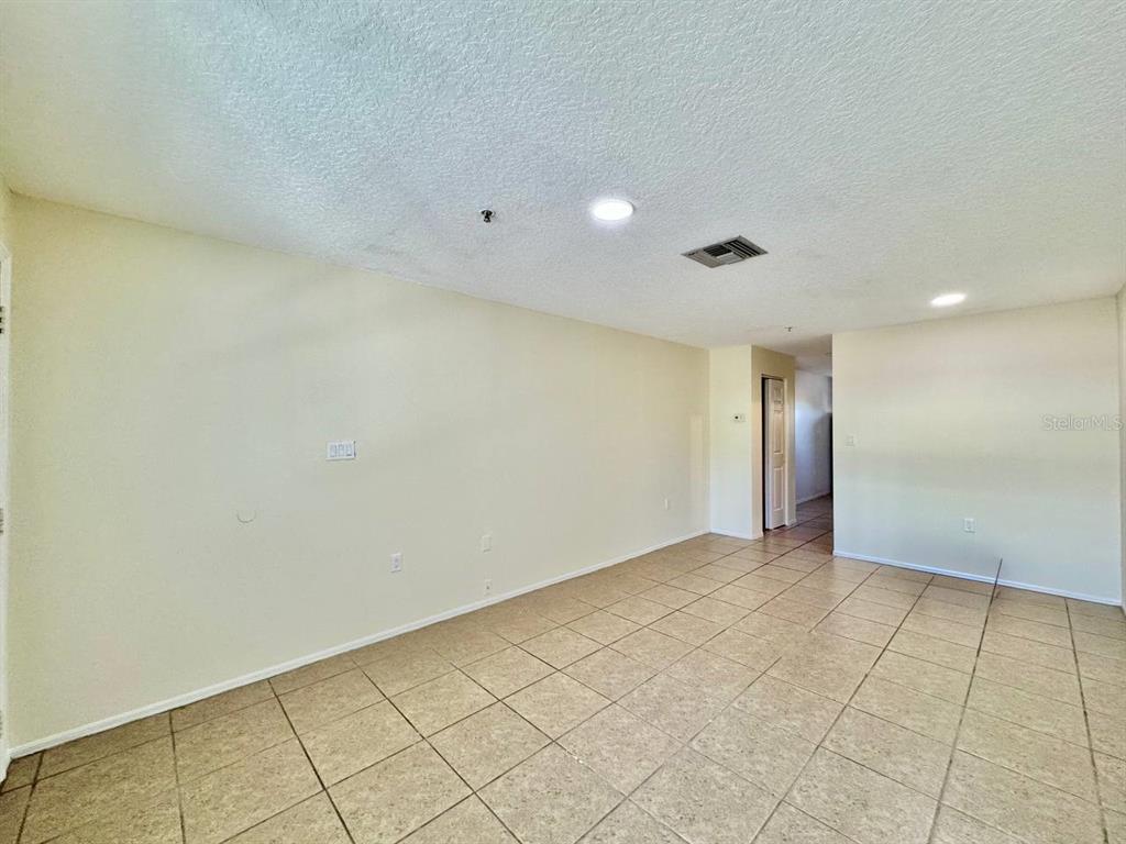 An empty room features beige walls, light-colored tile flooring, and recessed ceiling lighting — 5816 CONGRESS STREET UNIT 203, NEW PORT RICHEY, FL