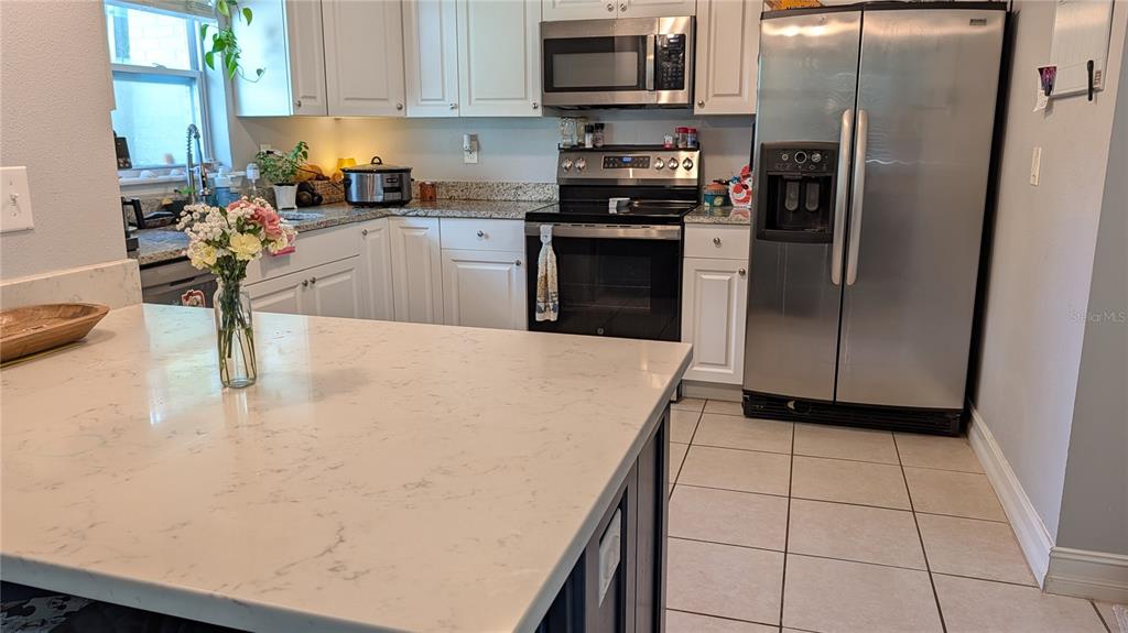 A kitchen features white cabinetry, stainless steel appliances, granite countertops, and a central island — 345 CANNON STREET, LAKELAND, FL