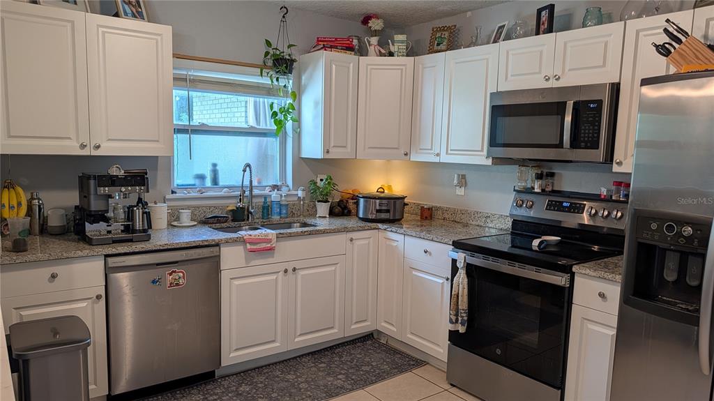 A kitchen features white cabinets, granite countertops, stainless steel appliances, and a window above the sink — 345 CANNON STREET, LAKELAND, FL