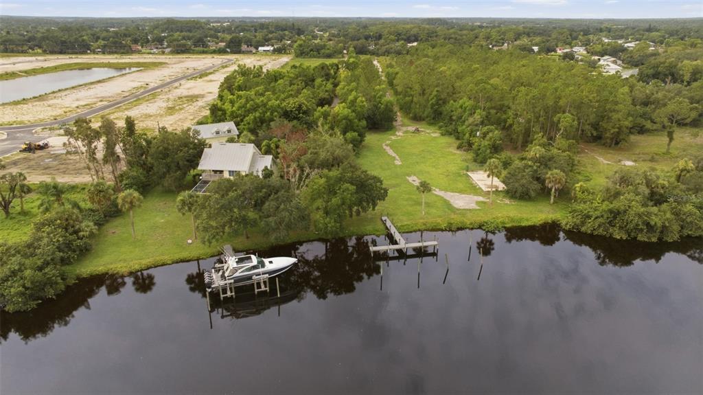 An aerial view shows a house with a boat docked at a pier on water — 13664 & 13668 MARQUETTE BOULEVARD, FORT MYERS, FL