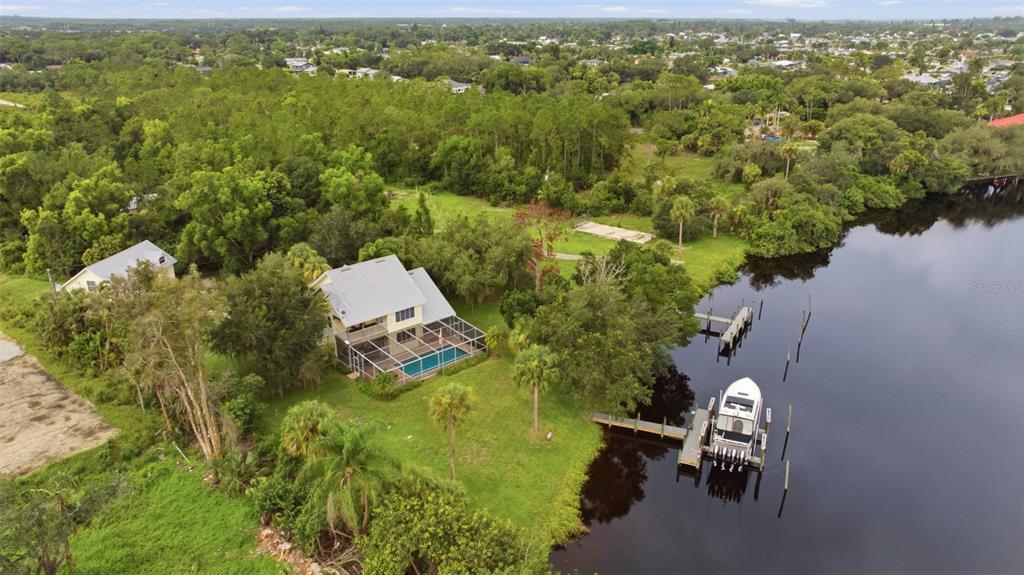 An aerial view shows a house with a pool and a boat docked on a river — 13664 & 13668 MARQUETTE BOULEVARD, FORT MYERS, FL
