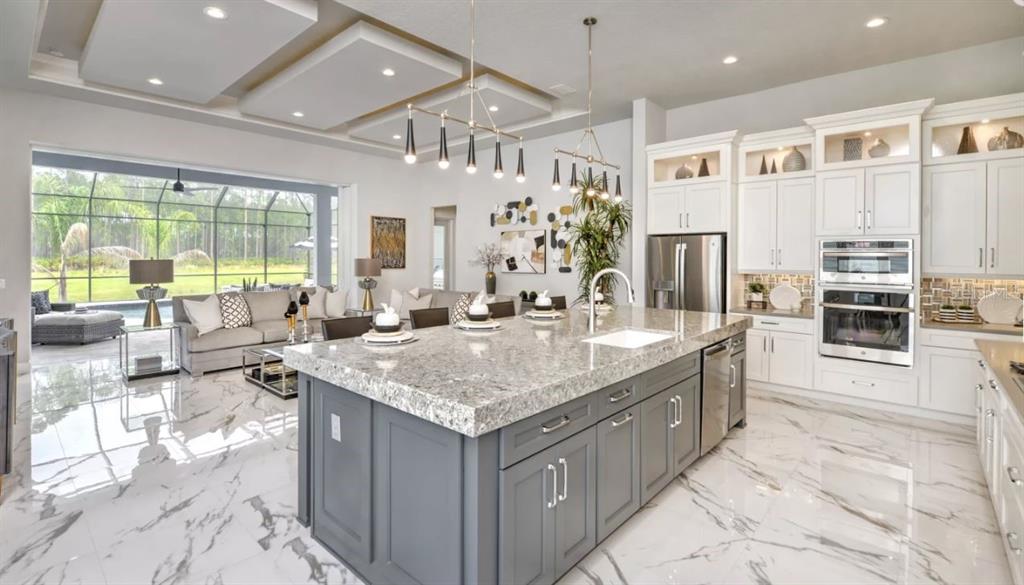 A modern kitchen with a gray island and white cabinets overlooks a living room area — 441 STIRLING BRIDGE DRIVE, ORMOND BEACH, FL
