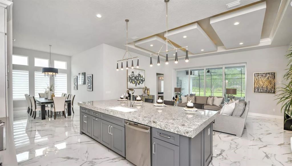 A modern kitchen with a large gray island, marble floors, and a dining area — 441 STIRLING BRIDGE DRIVE, ORMOND BEACH, FL