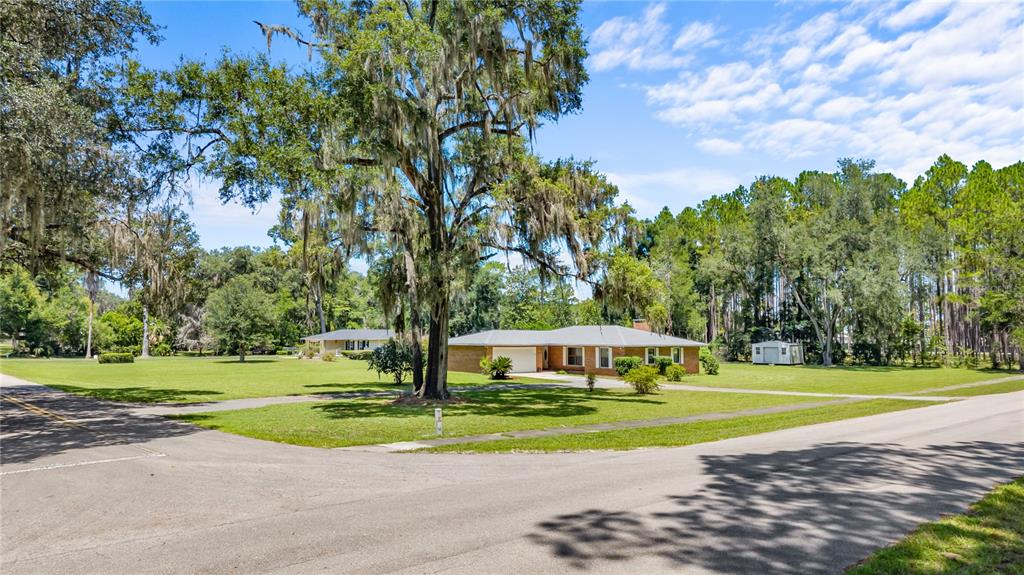 A single-story brick house sits on a large, grassy corner lot with mature oak trees — 1108 SW 2ND AVENUE, CHIEFLAND, FL