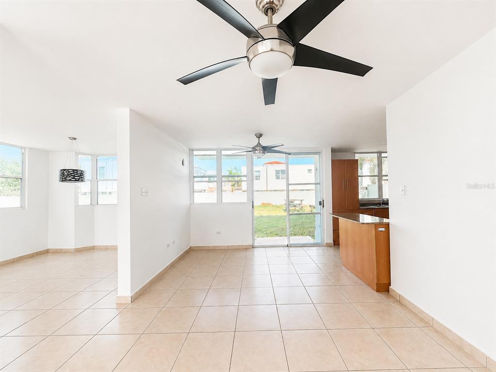 A kitchen with wood cabinets and a granite breakfast bar opens to a tiled dining area — Estancias de Cerro Gordo N CALLE NINOSHKA UNIT B-12, VEGA ALTA, PR