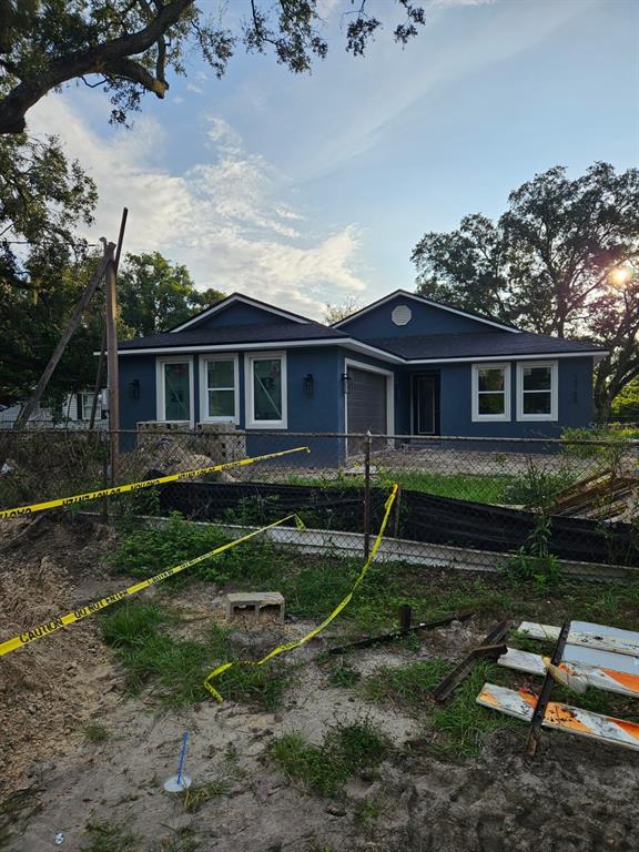 A newly constructed blue house with a garage and front yard behind a chain-link fence — 13105 N BOULEVARD, TAMPA, FL