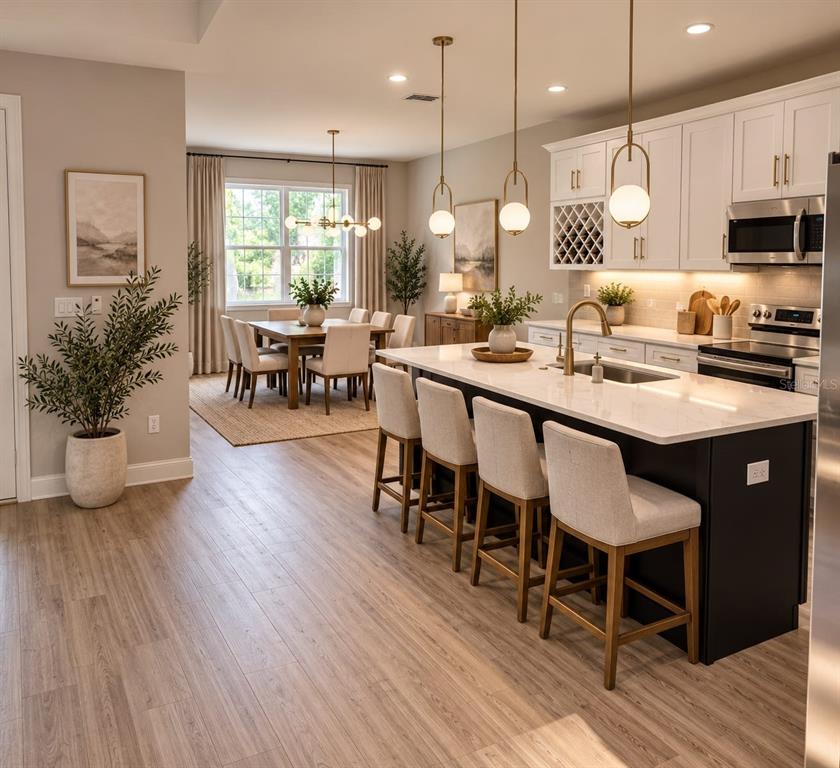 A modern kitchen with a dark island and white cabinets opens into a dining area — 13105 N BOULEVARD, TAMPA, FL
