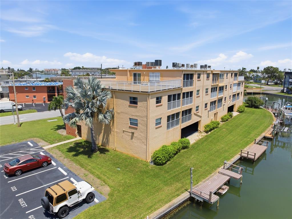 An aerial view shows a multi-story tan apartment building next to a canal with docks — 175 116TH AVENUE UNIT 206, TREASURE ISLAND, FL