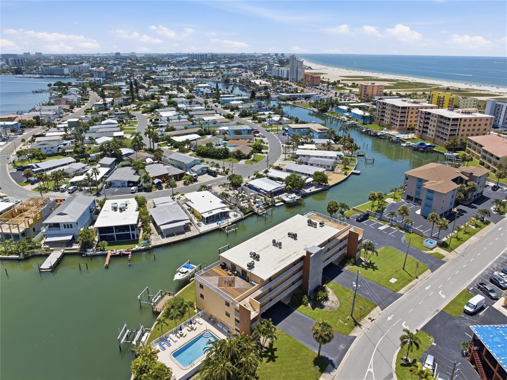 An aerial view shows a coastal neighborhood with canals, residential buildings, and a swimming pool — 175 116TH AVENUE UNIT 206, TREASURE ISLAND, FL