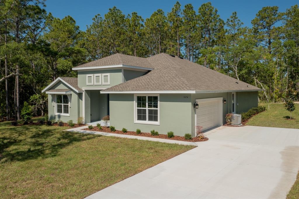 A light green single-story house with a two-car garage sits on a grassy lot — 1834 NW 79TH LOOP, OCALA, FL