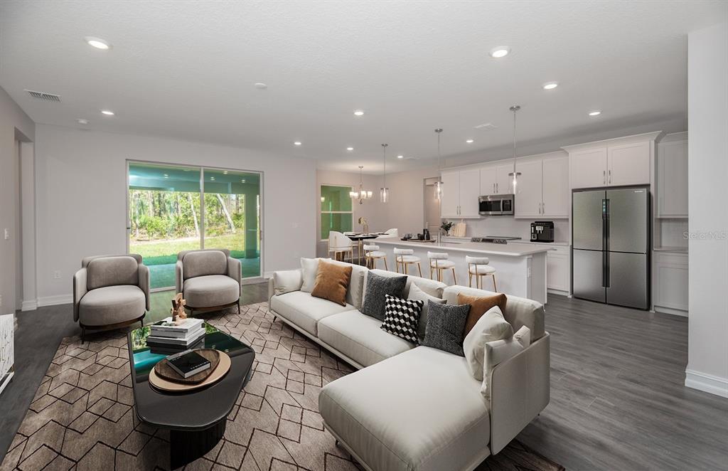 An open-concept living room and kitchen feature light gray flooring, white cabinetry, and sliding doors — 1834 NW 79TH LOOP, OCALA, FL