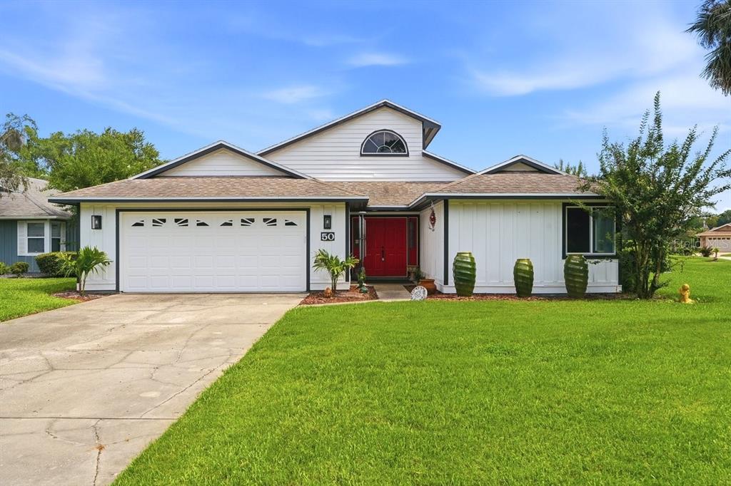 A single-story house with white siding, a red front door, and a two-car garage — 50 TREETOP CIRCLE, ORMOND BEACH, FL