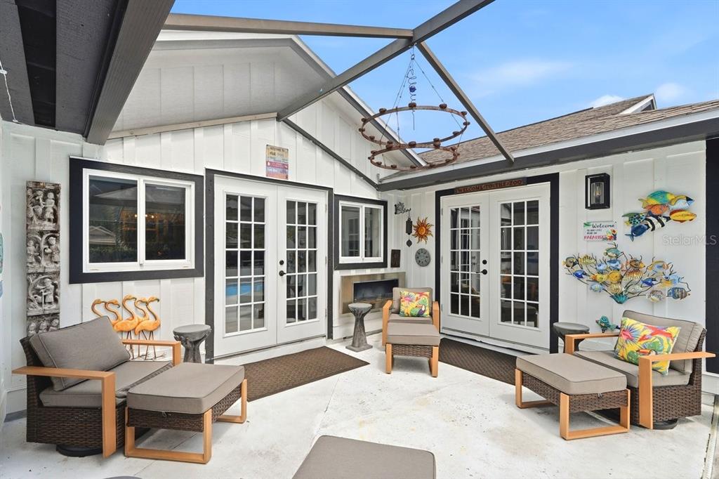 A covered outdoor patio features two sets of French doors, wicker furniture, and wall decorations — 50 TREETOP CIRCLE, ORMOND BEACH, FL