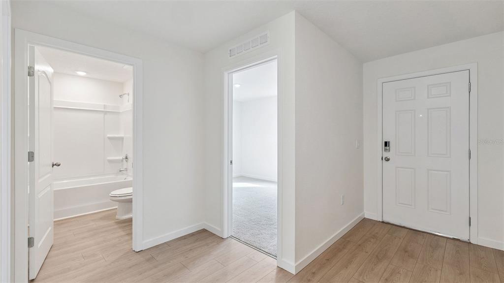An interior view showing a bathroom, a bedroom doorway, and an entryway with wood flooring — 139 HEIRLOOM DRIVE, ORMOND BEACH, FL