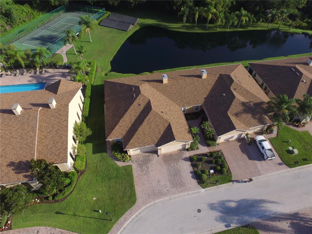 An aerial view shows residential buildings, a swimming pool, a tennis court, and a pond — 1307 INNSBRUCK CT, WINTER HAVEN, FL