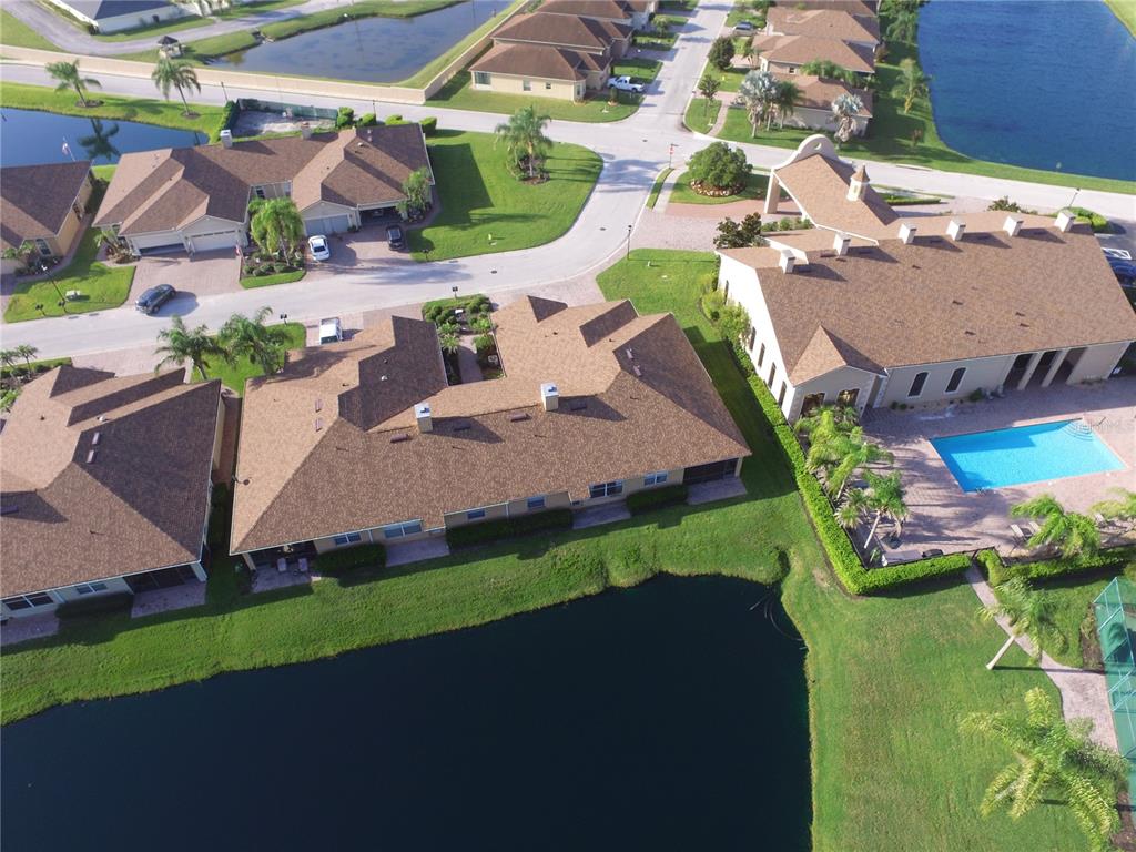 An aerial view shows several residential buildings with brown roofs surrounding a large pond — 1307 INNSBRUCK CT, WINTER HAVEN, FL