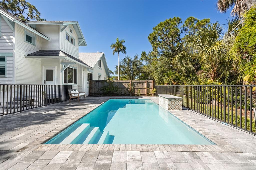 A rectangular swimming pool with a stone water feature sits on a paved patio — 1473 BARCELONA AVENUE, FORT MYERS, FL