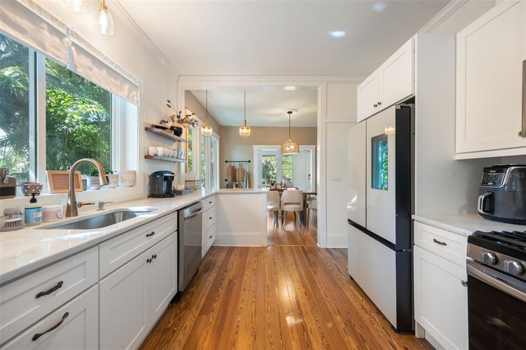 A bright kitchen features white cabinets, stainless steel appliances, and a window overlooking lush greenery — 1473 BARCELONA AVENUE, FORT MYERS, FL