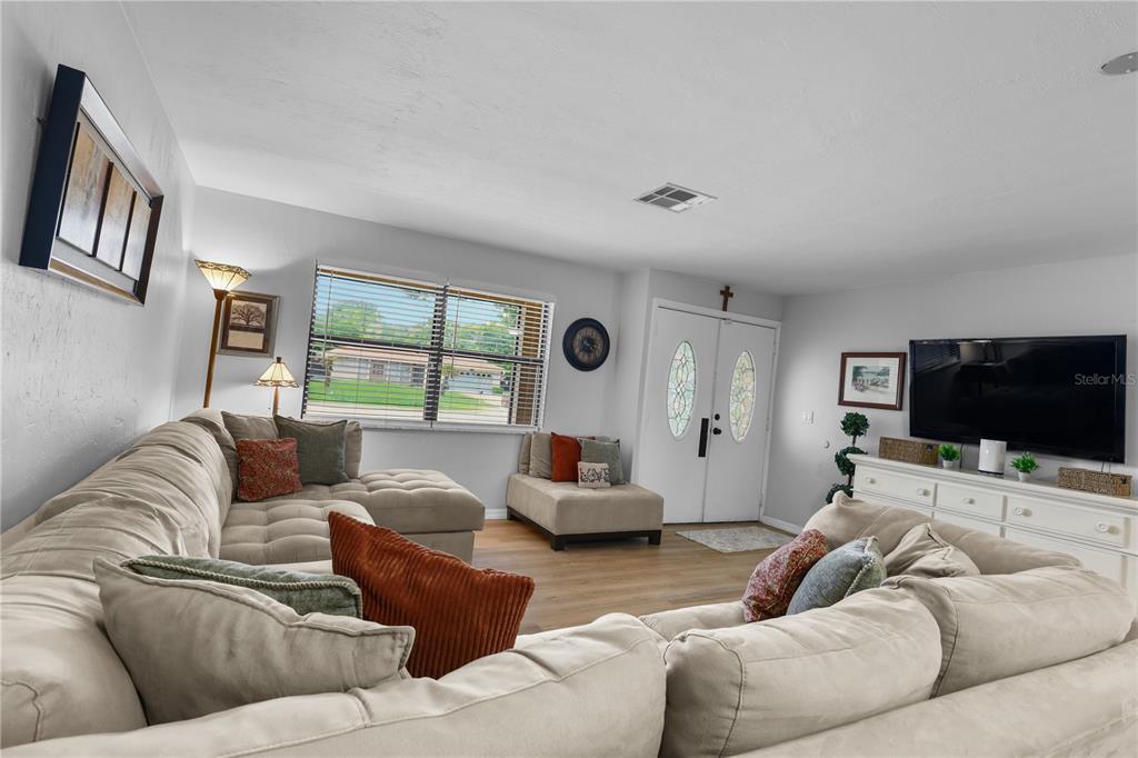 A living room features a large sectional sofa, a television console, and a front entryway — 4029 COUNTRY CLUB BOULEVARD, CAPE CORAL, FL