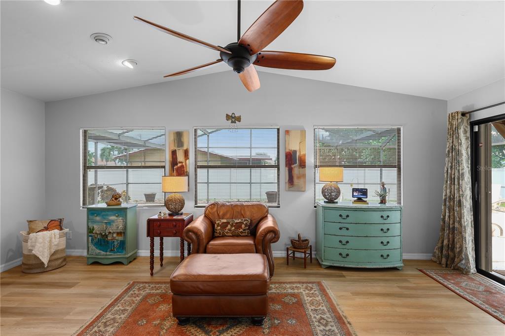 A living room features a leather armchair, ottoman, light wood flooring, and a ceiling fan — 4029 COUNTRY CLUB BOULEVARD, CAPE CORAL, FL
