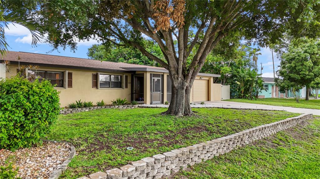 A single-story house with a tan exterior, a large front tree, and a stone retaining wall — 4029 COUNTRY CLUB BOULEVARD, CAPE CORAL, FL