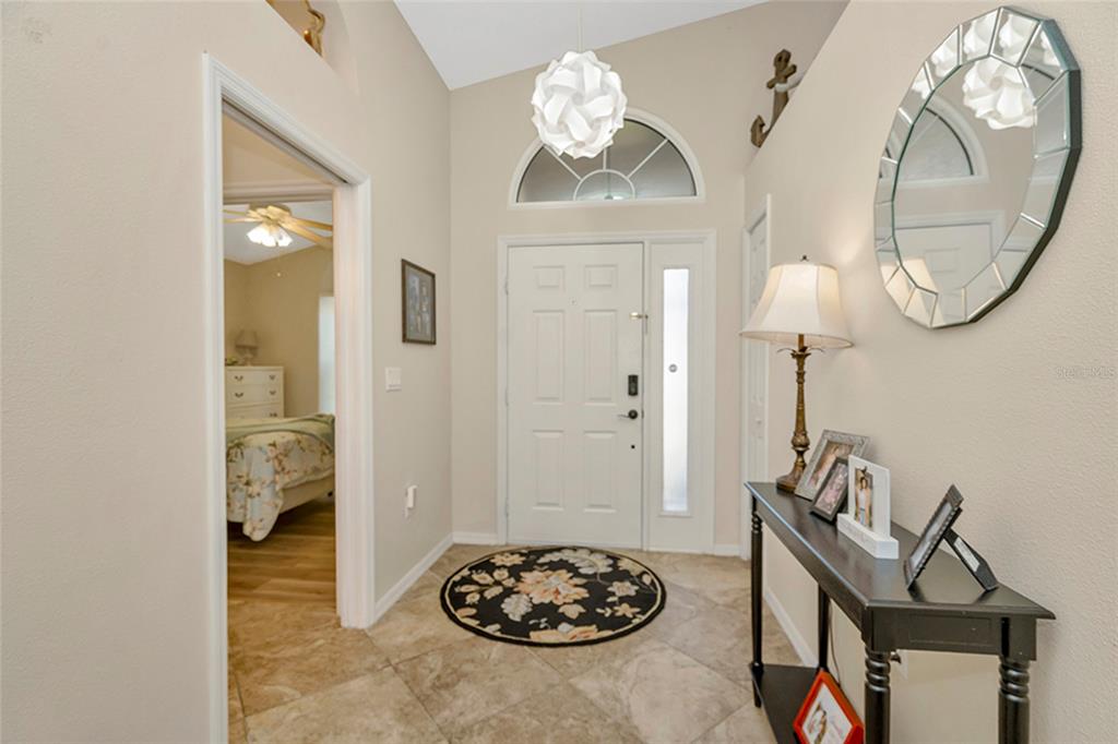 A tiled entryway features a white front door, a console table, and a round mirror — 3248 NOEMI DRIVE, NEW PORT RICHEY, FL