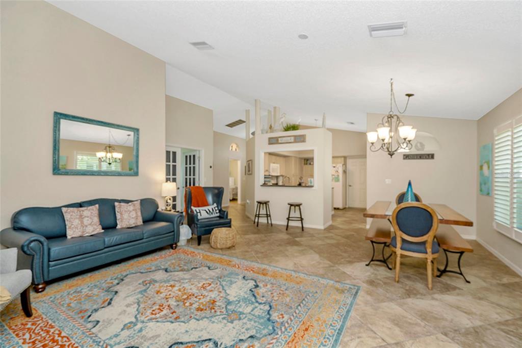 A living and dining area with tile floors, a blue sofa, and a kitchen pass-through — 3248 NOEMI DRIVE, NEW PORT RICHEY, FL