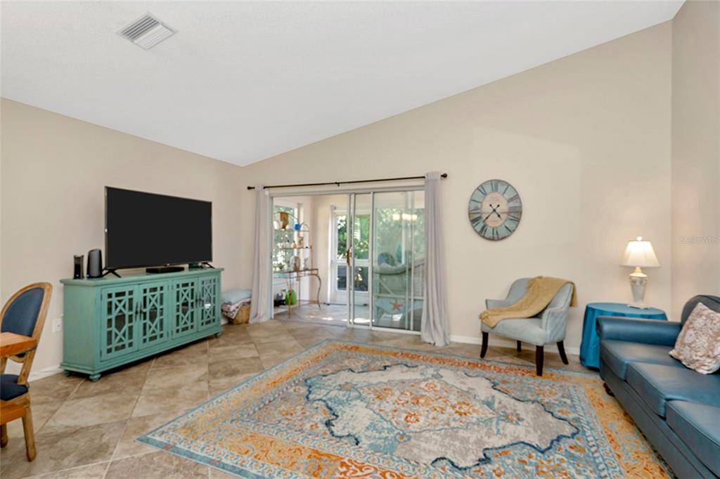 A living room features tile floors, a teal media console, a blue sofa, and sliding doors — 3248 NOEMI DRIVE, NEW PORT RICHEY, FL