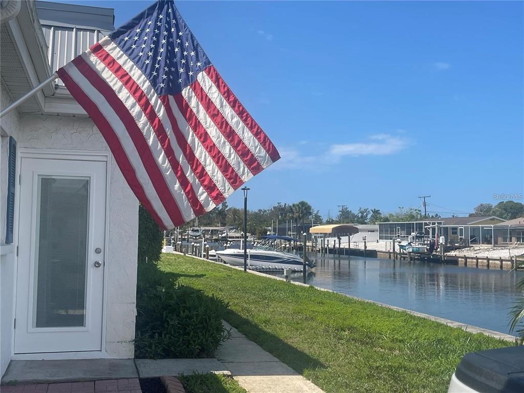 An American flag hangs on the exterior wall of a house overlooking a canal — 9819 HERNANDO COURT UNIT 29-A, BRADENTON, FL