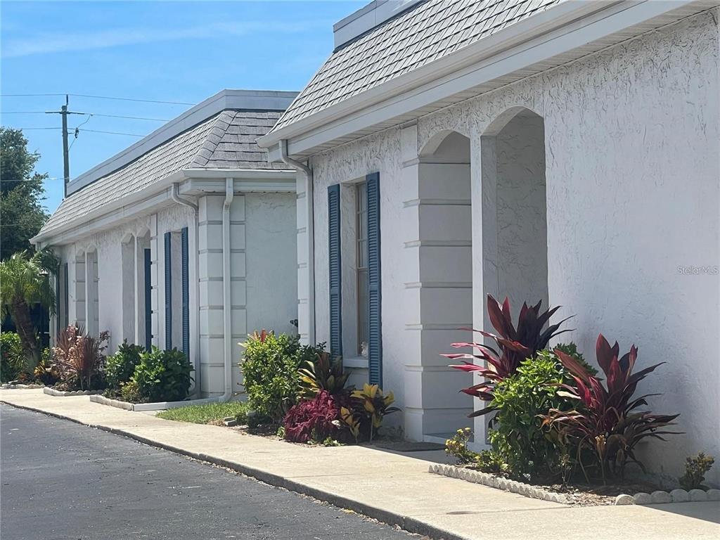 A row of white stucco buildings with blue shutters and gray shingled roofs — 9819 HERNANDO COURT UNIT 29-A, BRADENTON, FL