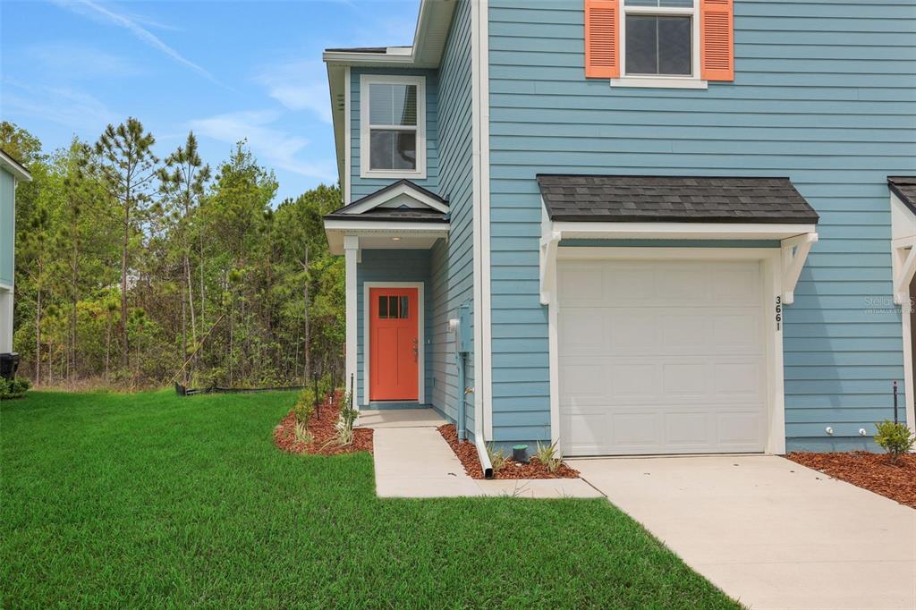 A blue two-story townhouse features an orange front door, a garage, and a grassy yard — 3779 ATHENIAN WAY, MIDDLEBURG, FL