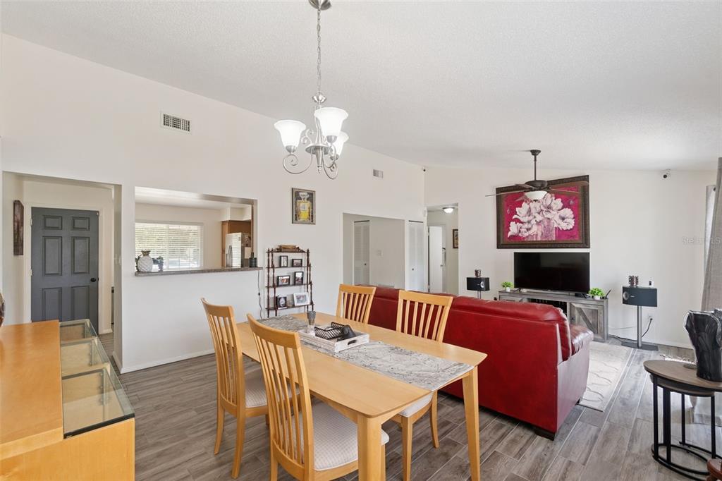A dining area with a wooden table and chairs sits adjacent to a living room — 1919 DEANNA DRIVE, APOPKA, FL