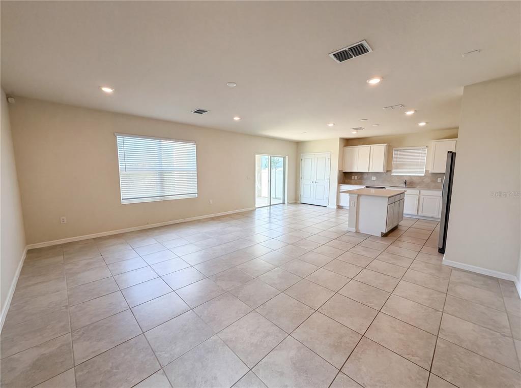 An open-concept living and kitchen area features light tile flooring and white cabinetry — 7768 SYRACUSE DRIVE, CLERMONT, FL