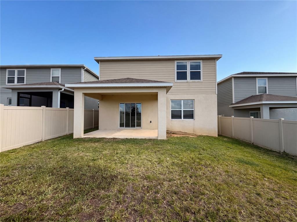 The rear exterior of a two-story house features a covered patio and a fenced yard — 7768 SYRACUSE DRIVE, CLERMONT, FL