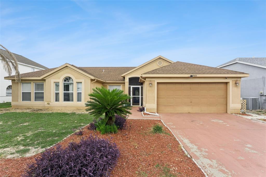 A single-story house with a tan exterior, a brown roof, and a two-car garage — 8611 PRIMROSE DRIVE, KISSIMMEE, FL