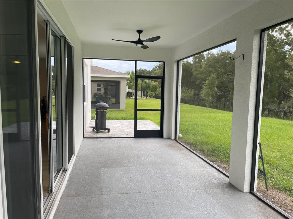 A screened-in patio features a concrete floor, a ceiling fan, and views of a grassy yard — 2994 GAVIN SKY DRIVE, KISSIMMEE, FL