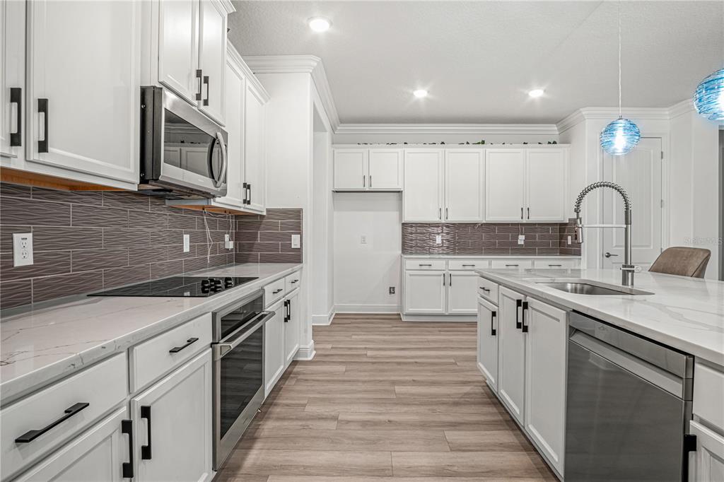 A modern kitchen features white cabinets, stainless steel appliances, a marble island, and gray tile — 1772 KILLIAN DRIVE NE, PALM BAY, FL