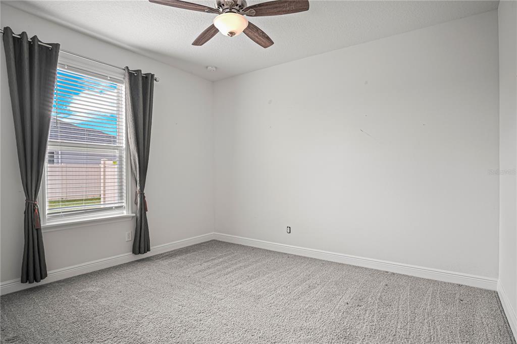 A bedroom with gray carpet, white walls, a ceiling fan, and a window with curtains — 1772 KILLIAN DRIVE NE, PALM BAY, FL